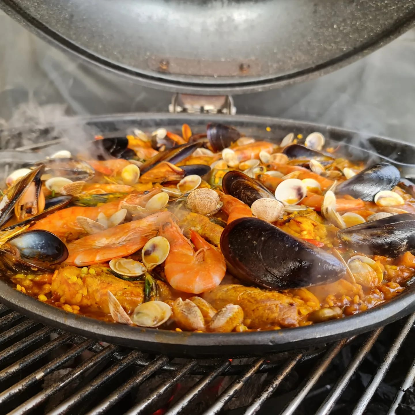 A seafood paella steaming on the grill