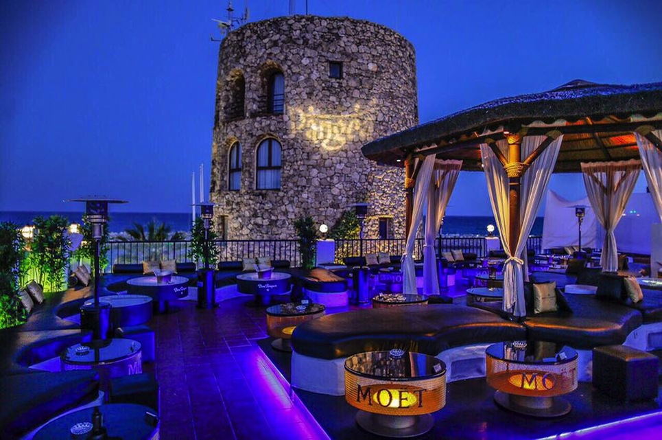 Pangea's terrace at night beside the old stone tower